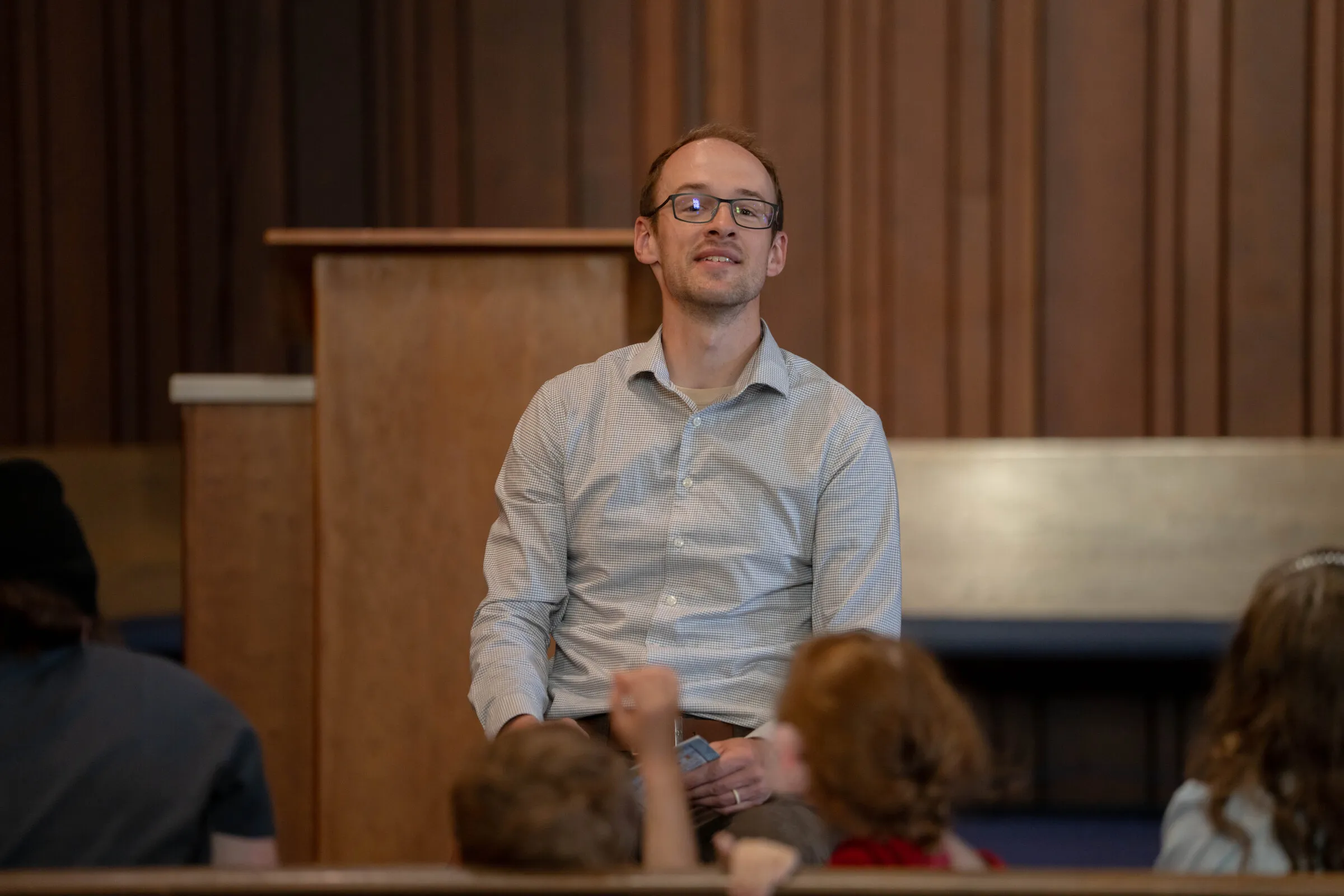 A man smiling while seated at the front of the church